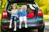 Little sisters sitting in a car just before leaving for a car vacation with their parents-family